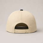 The back view of a beige baseball cap with an adjustable strap and a black button on top, set against a neutral gray background.
