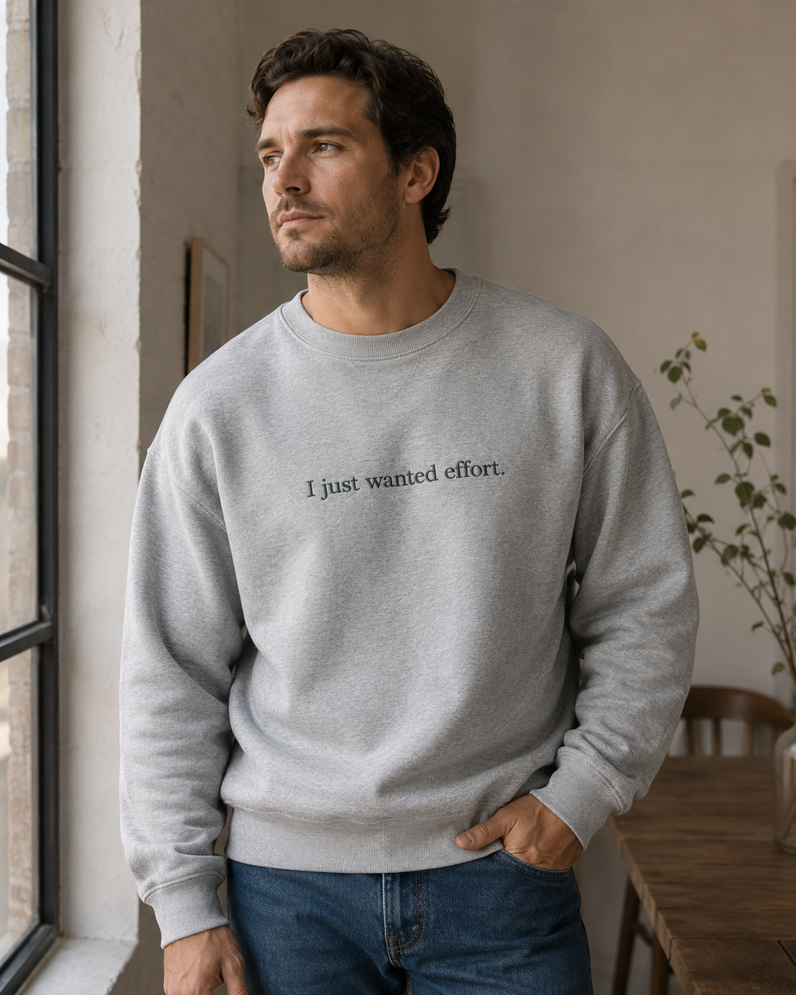 Folded Heather Gray crewneck sweatshirt with dark embroidery reading “I just wanted effort.” on a light background.